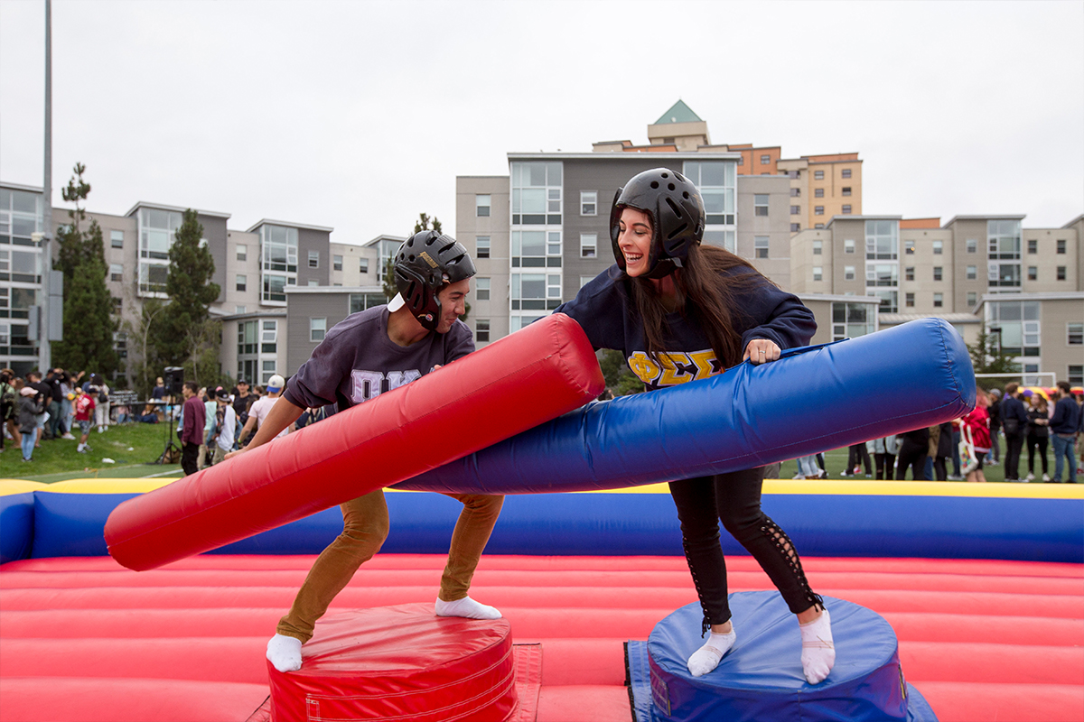 SF State students jousting on a red and blue bounce house  