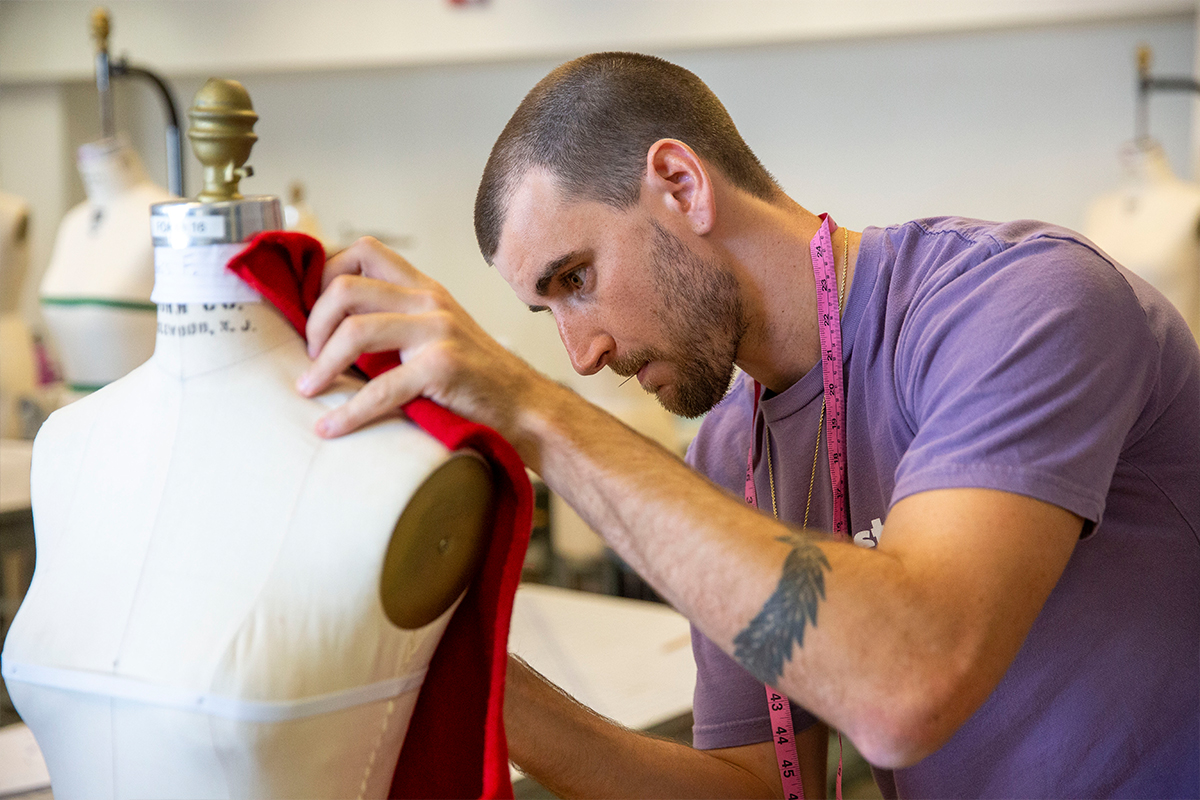 student pins red fabric to a mannequin 